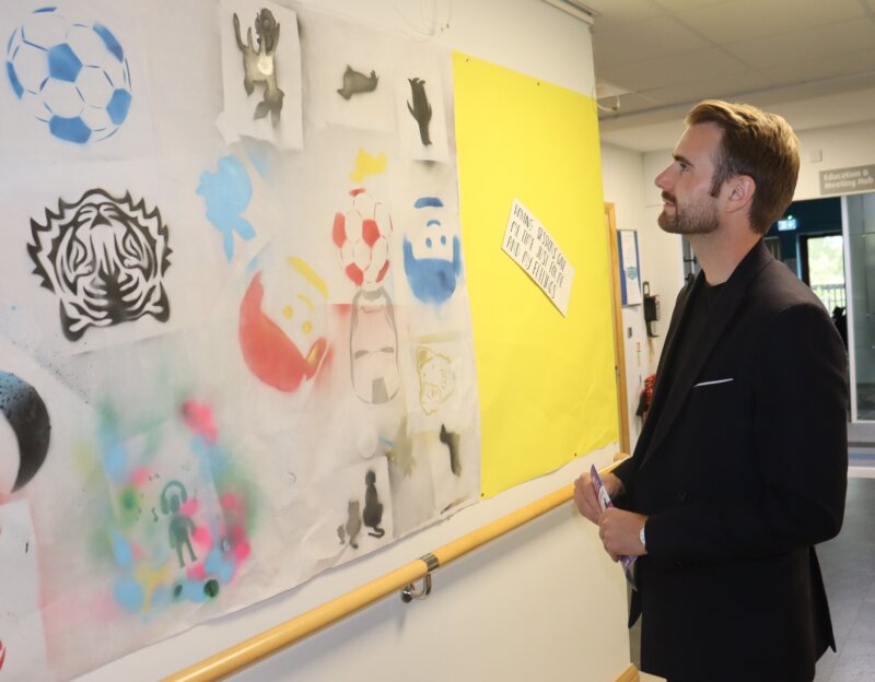 Patron Richard Jones views a gallery along a wall in the Farleigh offices of artwork created by children involved in the Yo Yo Project
